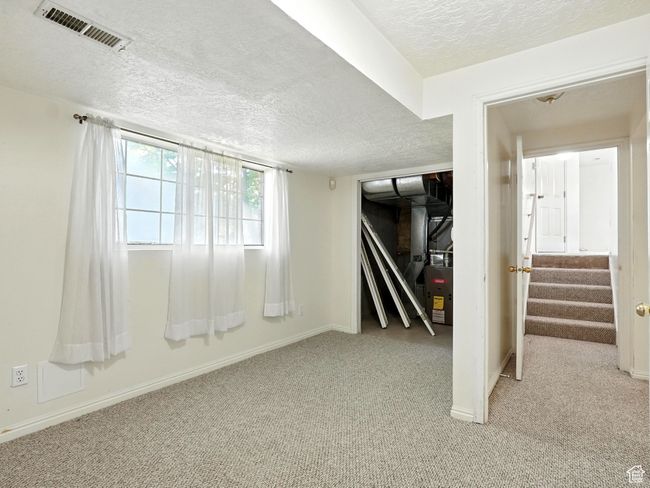 Below grade area with a textured ceiling, light carpet, and stairs | Image 12
