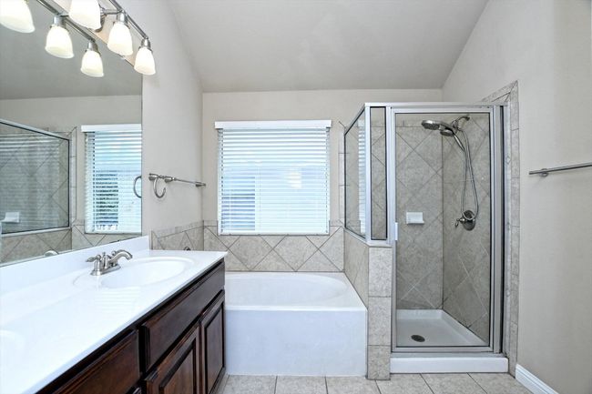 Full bathroom featuring tile patterned floors, lofted ceiling, a shower stall, vanity, and a bath | Image 19