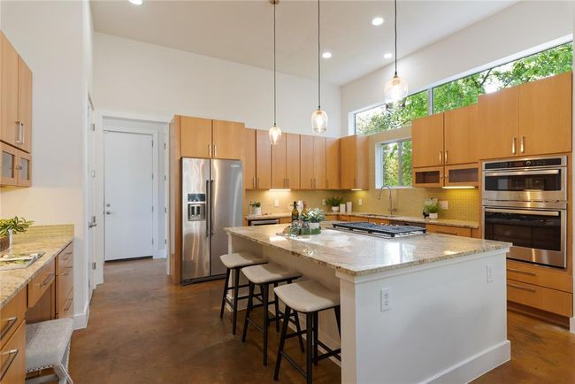 Kitchen with stainless steel appliances, tasteful backsplash, a kitchen breakfast bar, light stone counters, and a sink | Image 15