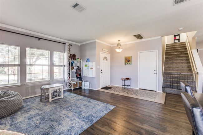 Living area featuring crown molding, stairs, wood finished floors, and baseboards | Image 9
