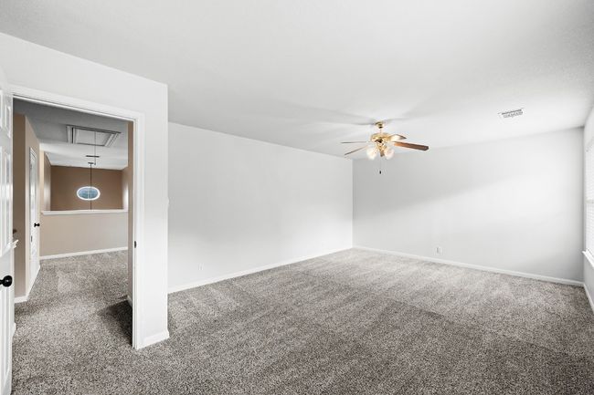 Carpeted empty room featuring a ceiling fan and attic access | Image 11