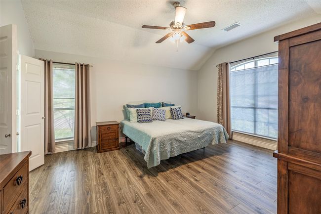 Bedroom with vaulted ceiling, wood finished floors, a textured ceiling, and ceiling fan | Image 20