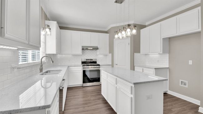 Kitchen featuring gas range, a sink, under cabinet range hood, decorative backsplash, and light stone counters | Image 6