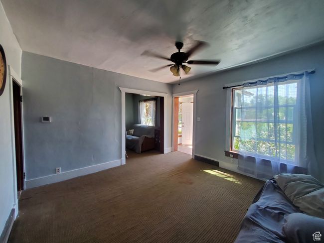 Carpeted living room featuring ceiling fan and baseboards | Image 4