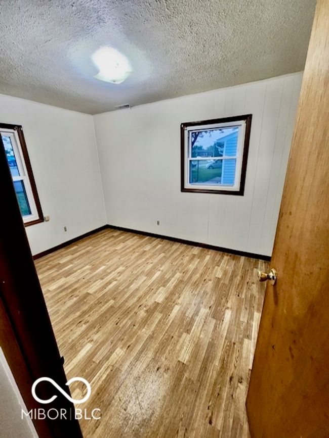 unfurnished room with wood finished floors, a textured ceiling, and baseboards | Image 6