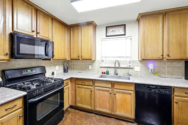This inviting kitchen offers classic wood cabinetry, durable countertops, and a full suite of appliances including a gas cooktop and dishwasher, blending practicality with warmth. | Image 8