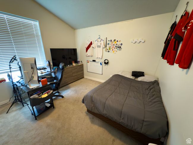 Bedroom featuring carpet floors, vaulted ceiling, and an office area | Image 16