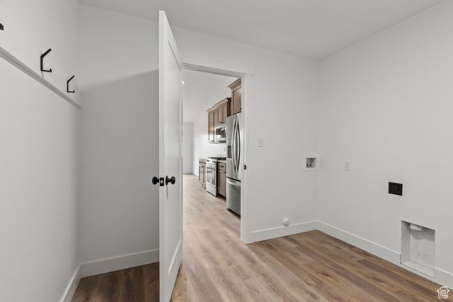 Clothes washing area featuring hookup for an electric dryer, washer hookup, light wood finished floors, and baseboards | Image 20