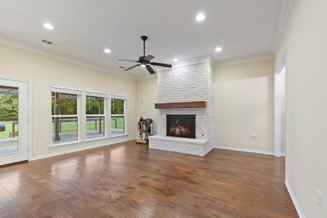 Unfurnished living room with crown molding, visible vents, a ceiling fan, and a brick fireplace | Image 5