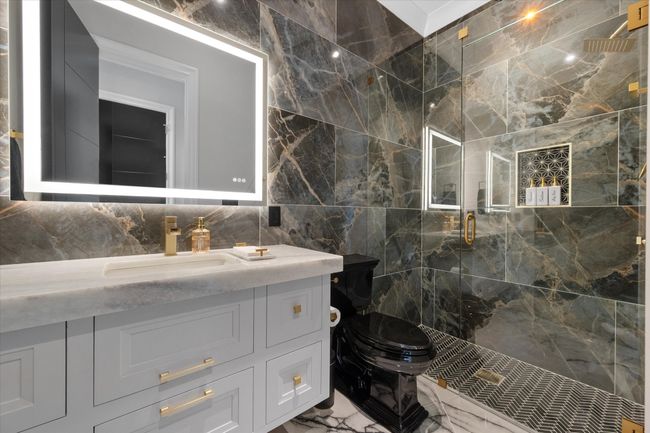 Bathroom featuring tile walls, a shower stall, vanity, toilet, and marble finish floor | Image 22