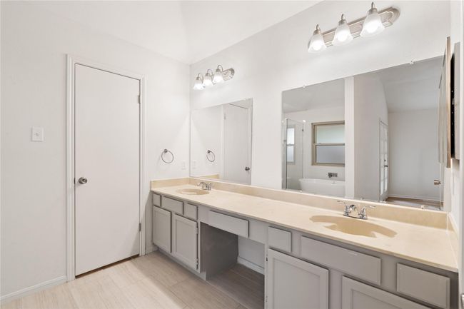 Primary bath with long double vanity, updated lighting, and neutral finishes. | Image 16