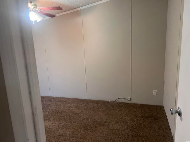 Carpeted spare room featuring ceiling fan and a textured ceiling | Image 17