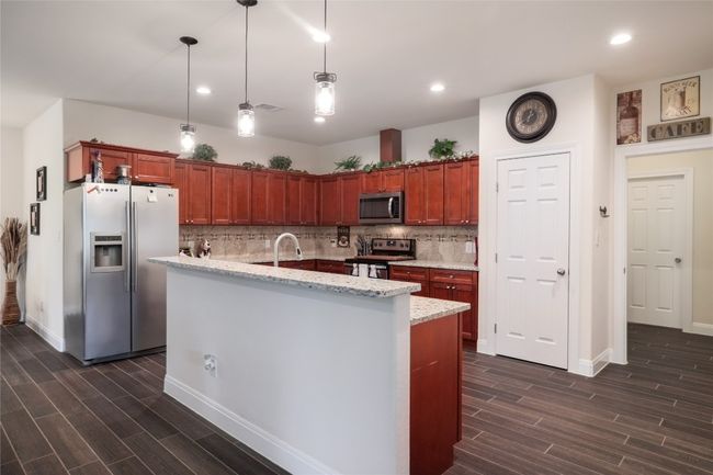 Kitchen featuring stainless steel appliances, breakfast bar with granite countertop, adorned with pendant lightings and recess lighting, too. | Image 13