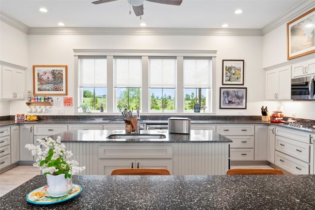 Kitchen with dark stone counters, stainless steel appliances, ornamental molding, and white cabinetry | Image 12