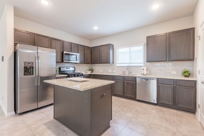 Kitchen with tasteful backsplash, dark brown cabinets, appliances with stainless steel finishes, and a sink | Image 13
