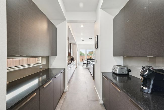 Kitchen featuring modern cabinets, light tile patterned floors, dark stone counters, dark brown cabinets, and recessed lighting | Image 9