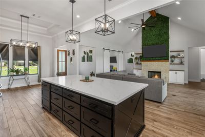 Kitchen featuring hanging light fixtures, a kitchen island, a fireplace, ceiling fan with notable chandelier, and a barn door | Image 3