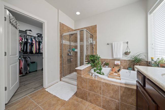 Bathroom featuring a bath, a shower stall, tile patterned flooring, and a walk in closet | Image 16