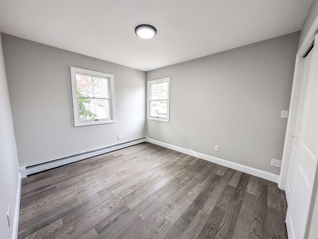 Empty room featuring a baseboard heating unit, dark wood-style floors, and baseboards | Image 12