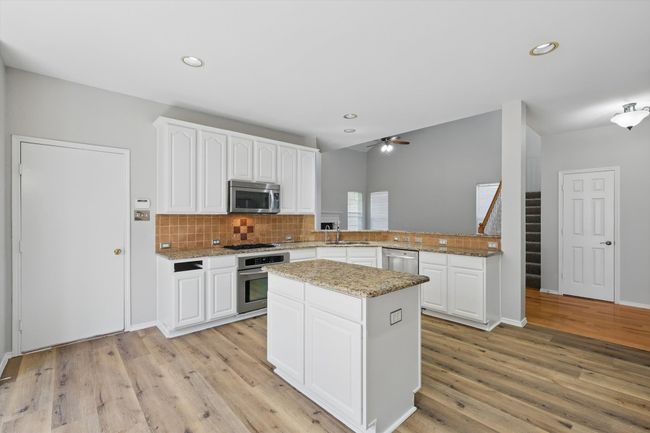 Kitchen featuring stainless steel appliances, a sink, a ceiling fan, light wood-type flooring, and recessed lighting | Image 11