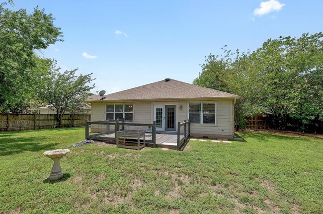 Back of property with a fenced backyard, a deck, french doors, and a shingled roof | Image 25