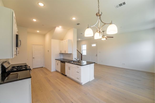 Kitchen featuring appliances with stainless steel finishes, a sink, dark countertops, and visible vents | Image 4