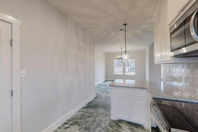 Kitchen featuring white cabinets, visible vents, appliances with stainless steel finishes, light stone counters, and baseboards | Image 10