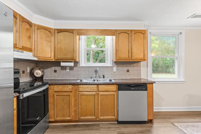 Kitchen with appliances with stainless steel finishes, under cabinet range hood, a sink, decorative backsplash, and a textured ceiling | Image 26
