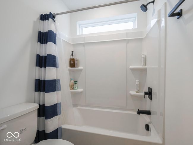 bathroom featuring shower / bathtub combination with curtain and toilet | Image 47