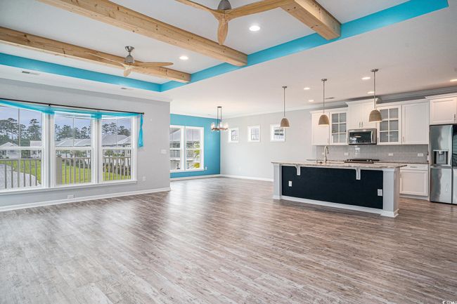 Kitchen featuring refrigerator with ice dispenser, ceiling fan, open floor plan, stainless steel microwave, and a kitchen breakfast bar | Image 4