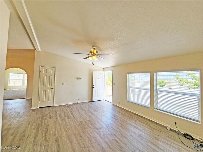 Unfurnished living room featuring ceiling fan, a textured ceiling, baseboards, arched walkways, and wood finished floors | Image 6
