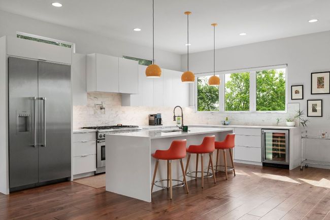 Chef's kitchen with custom cabinetry, quartz countertops, island with dual waterfalls, Thermador appliances, dual ovens, pot filler, wine chiller, marble backsplash & lovely natural light. | Image 6