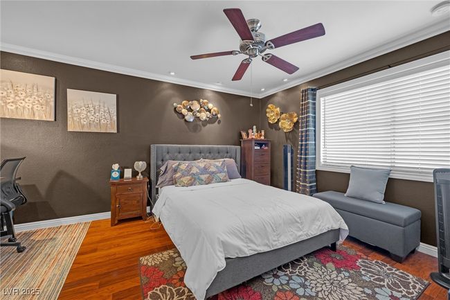 Bedroom with baseboards, ornamental molding, wood finished floors, and a ceiling fan | Image 15