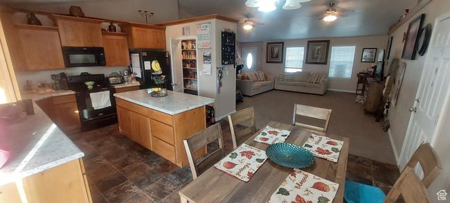 Kitchen featuring black appliances, ceiling fan, light countertops, open floor plan, and a kitchen island | Image 10