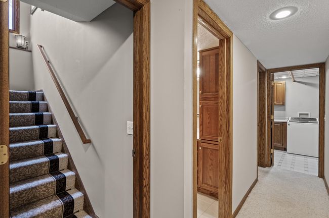 Lower level hallway headed to the 3/4 bathroom, a bedroom and the laundry room. The stairs have been protected by the runner which can be easily removed if you prefer a different look | Image 37