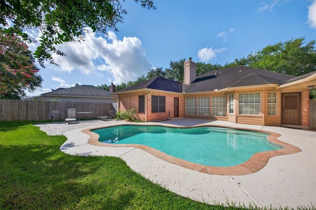 This photo showcases a charming backyard with a private swimming pool surrounded by a well-maintained patio and lawn. The house features large windows and a brick exterior, enhancing its inviting atmosphere. Perfect for relaxation and outdoor entertaining. | Image 41