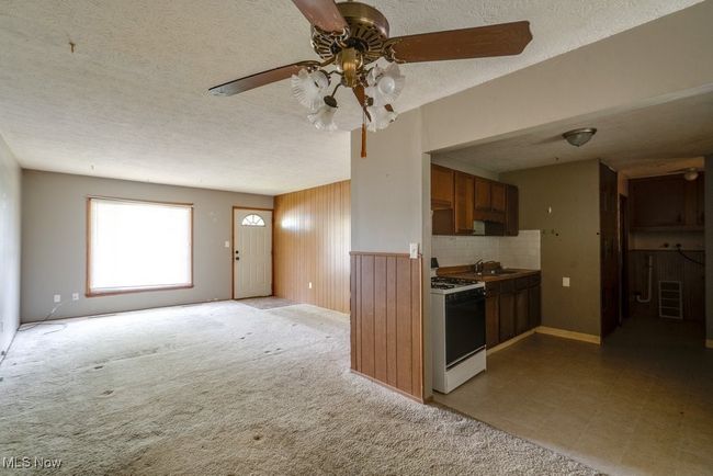 Kitchen featuring gas range gas stove, ceiling fan, a sink, a textured ceiling, and decorative backsplash | Image 14