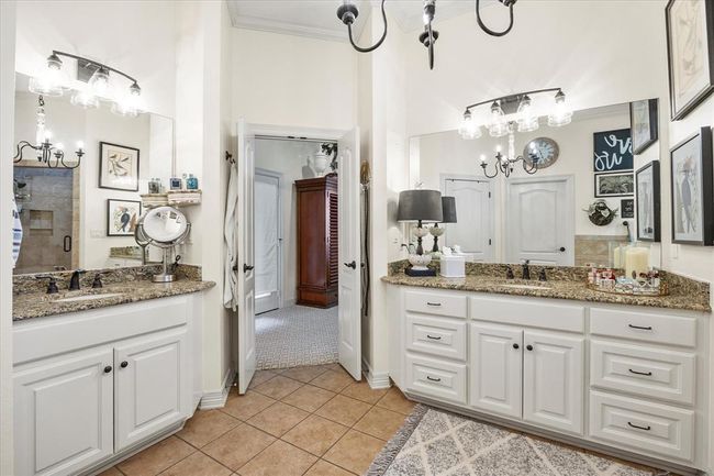 Bathroom featuring crown molding, dual bowl vanity, a chandelier, and tile flooring | Image 30
