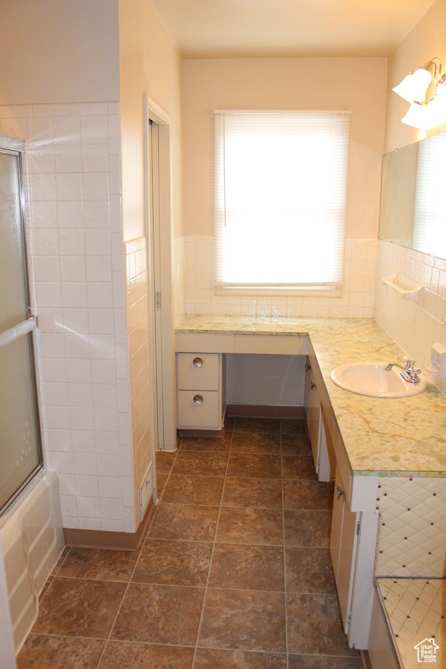 Bathroom featuring vanity, tile walls, a wainscoted wall, and combined bath / shower with glass door | Image 11