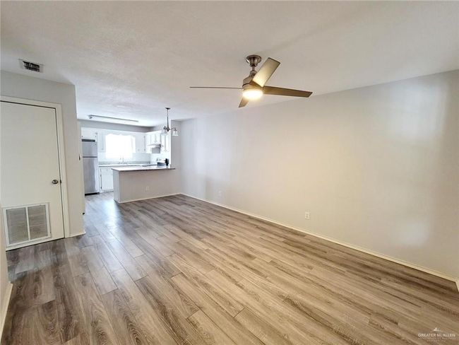 Unfurnished living room with wood finished floors, ceiling fan, and a chandelier | Image 16