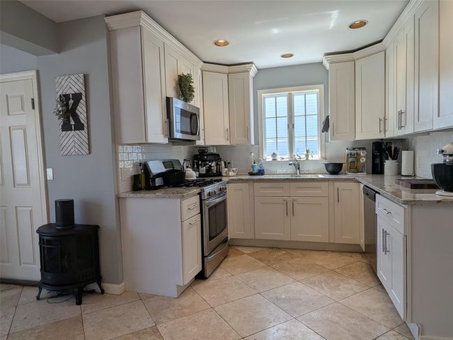 Updated large kitchen with stainless steel appliances, decorative backsplash, deep sink, stone countertops, and recessed lighting | Image 9