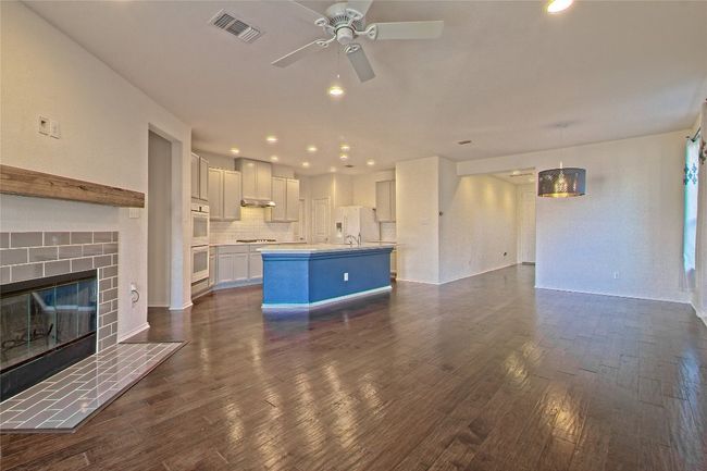 Unfurnished living room with dark wood-style floors, a ceiling fan, recessed lighting, and a tiled fireplace | Image 9