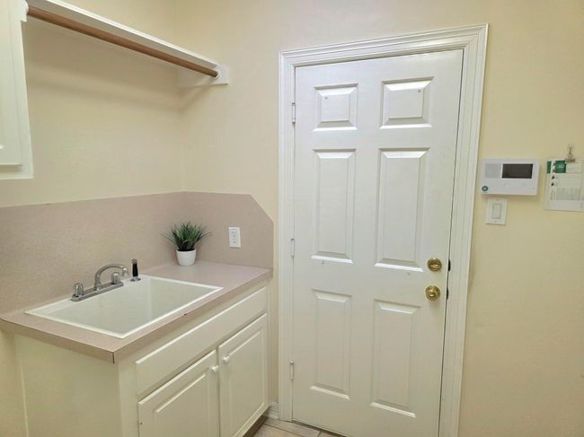 Convenient laundry room featuring a utility sink, ample counter space, and storage cabinets. Ideal for efficient household chores. | Image 41