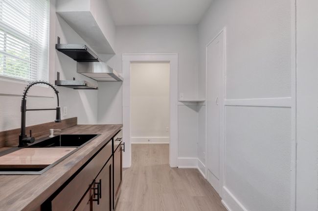 Kitchen with open shelves, light wood-style flooring, and butcher block countertops | Image 10
