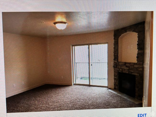 Unfurnished living room featuring carpet flooring and a fireplace | Image 4