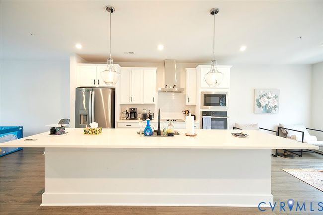 Kitchen with a large island, stainless steel appliances, light wood-type flooring, white cabinetry, and recessed lighting | Image 37