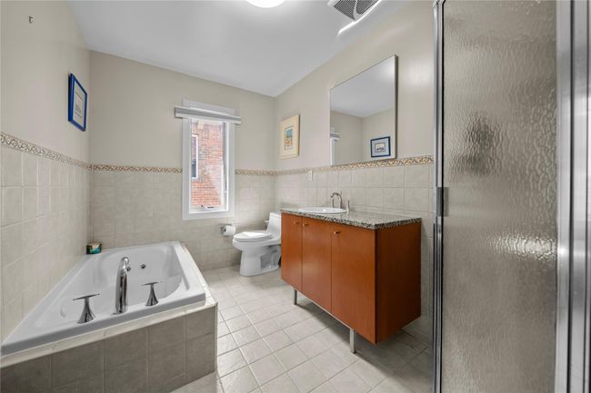 Full bath with tile patterned floors, tile walls, vanity, a stall shower, and a jetted tub | Image 21