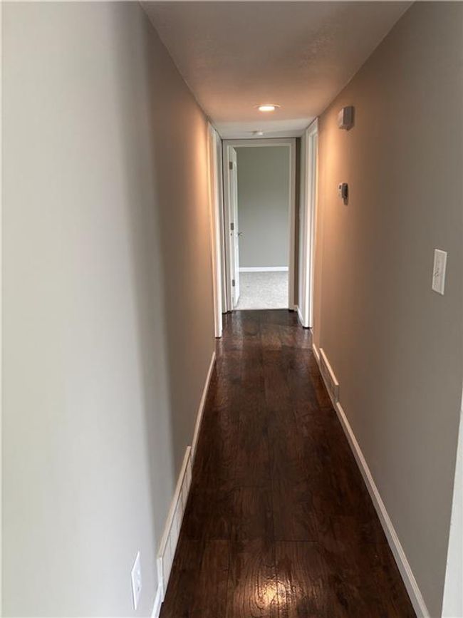 Hall with dark wood-type flooring, visible vents, and baseboards | Image 14