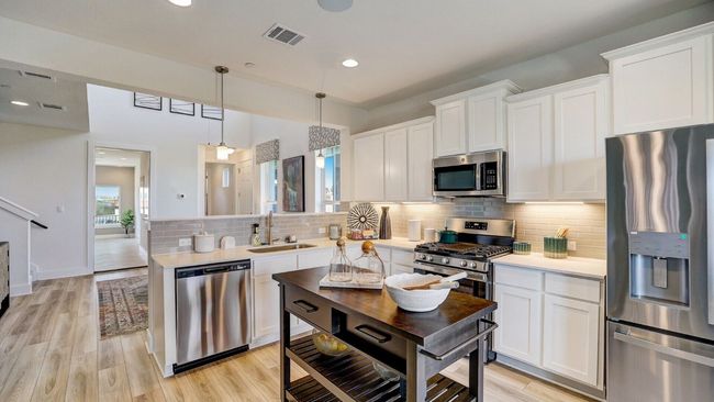 Kitchen with stainless steel appliances, a sink, a peninsula, light countertops, and white cabinets | Image 4