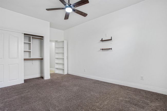 Unfurnished bedroom with dark carpet, a closet, baseboards, and ceiling fan | Image 30